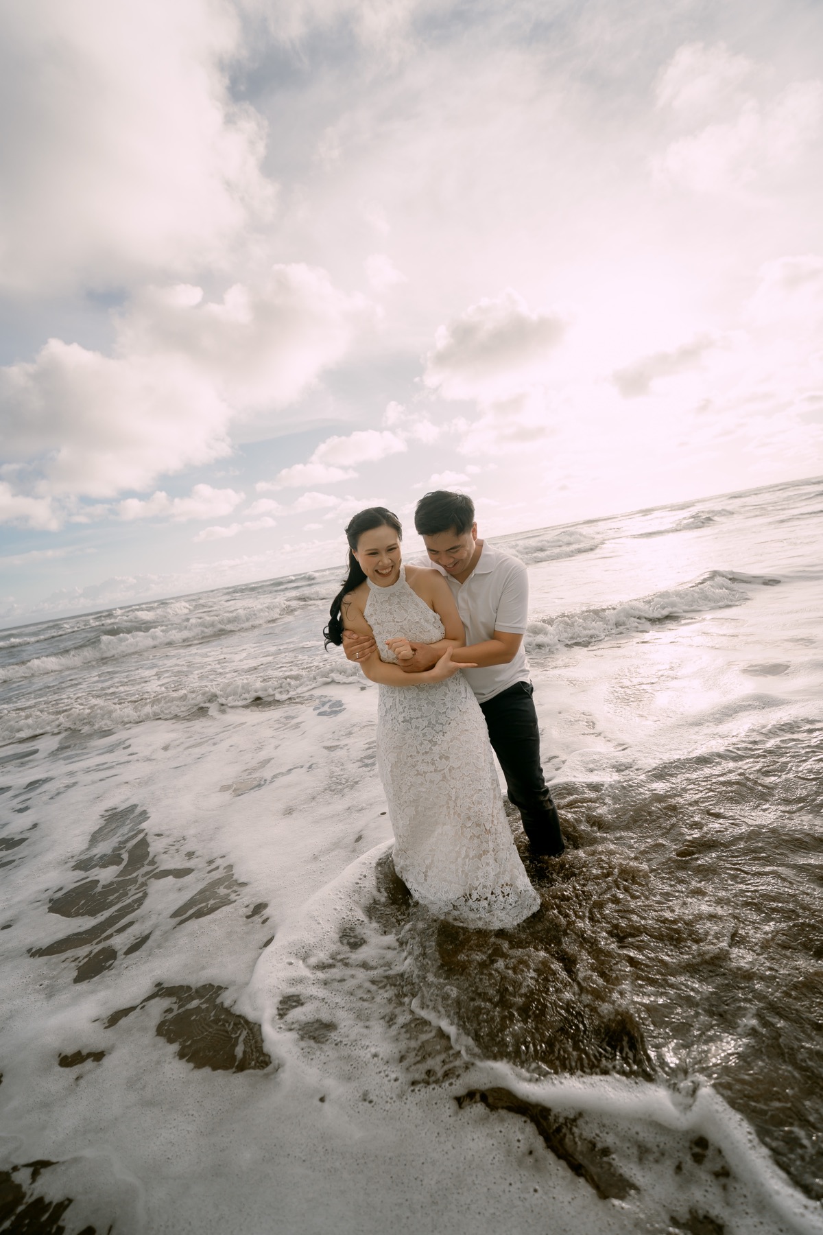 Angelia and Daniel laugh together in the surf.