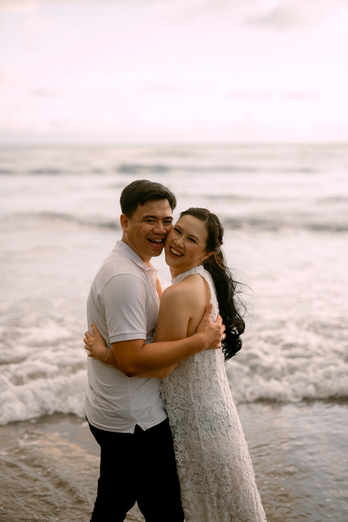 Angelia and Daniel smile together by the sea.