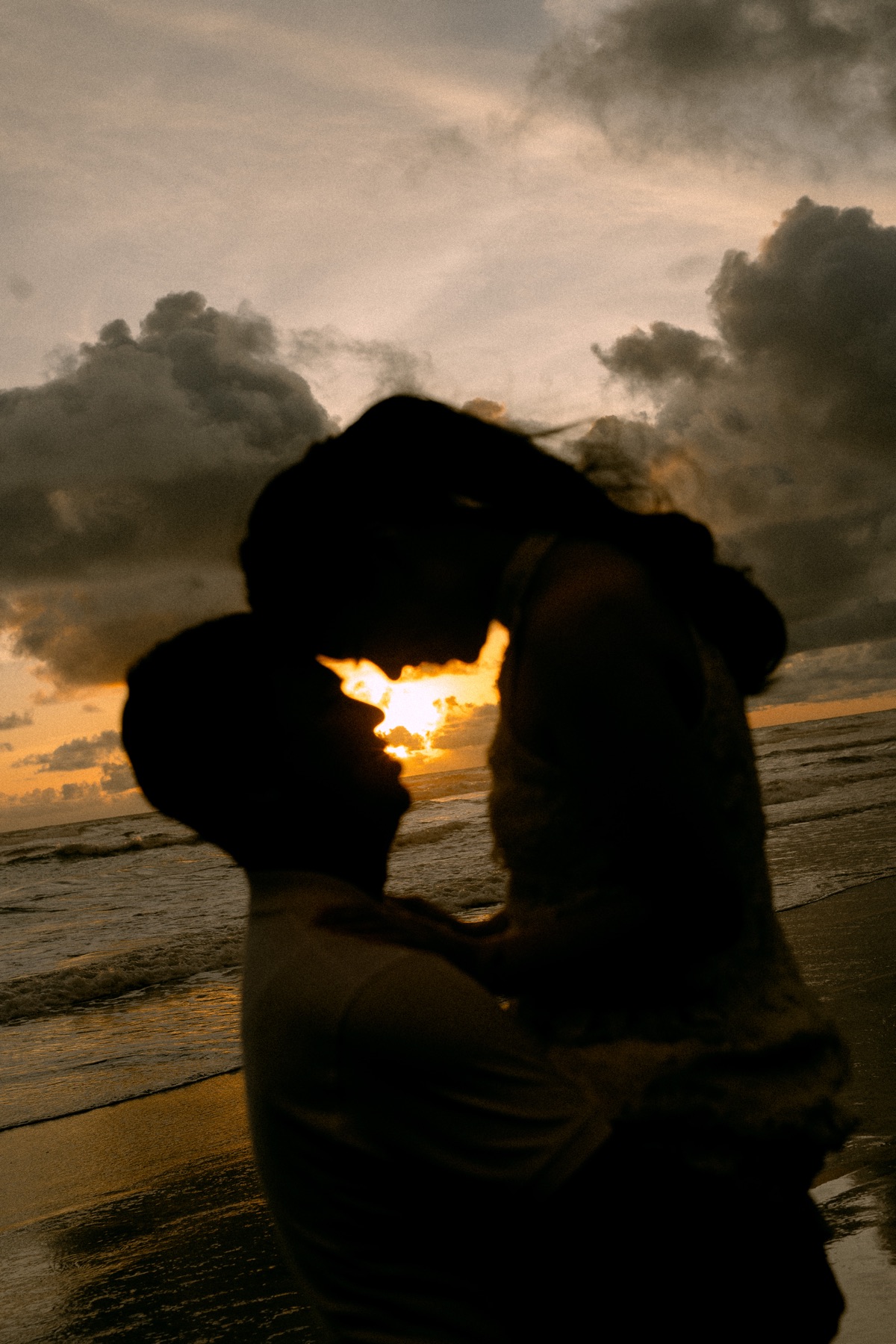 Angelia and Daniel embrace at sunset on the beach.